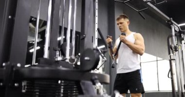 Sporcu modern spor salonunda silah pompalamak için eğitim makinesini kullanır. Spor giyim sektöründe formda bir erkek ağır çekimde egzersiz ekipmanı kullanır.