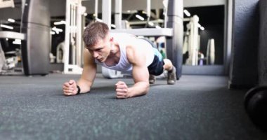 Formda bir erkek modern spor salonunda vücudu güçlendirmek için tahta pozlar verir. Formda sporcu, ağır çekimden sonra modern spor salonunda yoğun egzersizden hoşlanır.