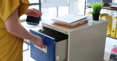 Kadın sekreter çekmeceyi açar ve belgeleri ofise koyar. Depolama iş belgeleri
