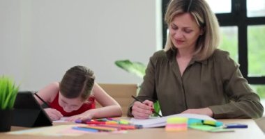 Çekici anne ve küçük kız renkli kalemlerle kağıda resim çiziyorlar. Sevgi dolu aile iletişimden ve ortak yaratıcı hobiden hoşlanır.