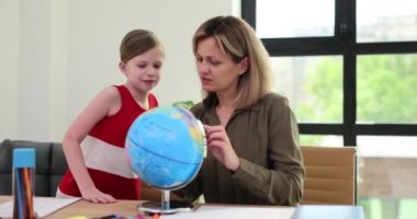 Anne ve kızı evde dünya ile coğrafya ödevi yapıyor. Öğretmen dünya haritasını okul kızına gösteriyor