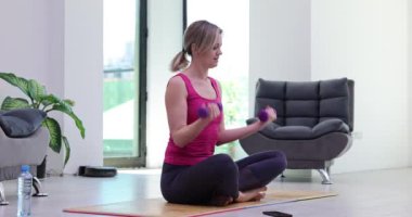 Halterli aktif atletik kadın kaslarını ve pazılarını şişiriyor ve telefonla mesajlaşarak dikkati dağılıyor. Spor hedefinin tutturulması ve spor kasılmalarının kaybedilmesi