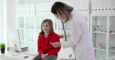 Pediyatrist steteskoplu küçük bir kızın ciğerlerini dinler. Çocuklarda sağlık izleme