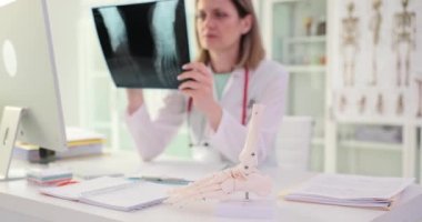 Doktor kırık ayağın röntgenine bakıyor. Ayak ağrısı, teşhis ve tedaviye neden olur.