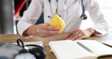 Doktor lezzetli sarı armudu elinde tutuyor. Sağlıklı yemek ve diyet
