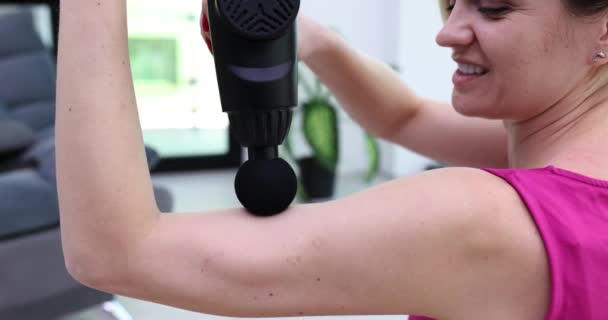 女性は振動マッサージでマッサージリラックスハンドマッサージを行います マッサージ銃を使用して腕の筋肉をマッサージ — ストック動画