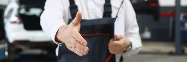 stock image Closeup of auto mechanic greeting someone and offering handshake working in auto repair shop. Car service contract concept