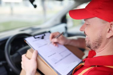 Kurye şoförü arabadaki teslimat makbuzlarını doldurur. Mal teslimatı ve lojistik konsepti