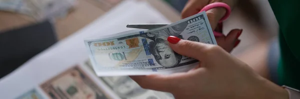 Criminal cuts dollar bills with scissors printed on printer closeup. Counterfeit money concept