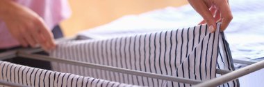 Woman hands hang clothes on dryer at home. Drying wet clothes concept