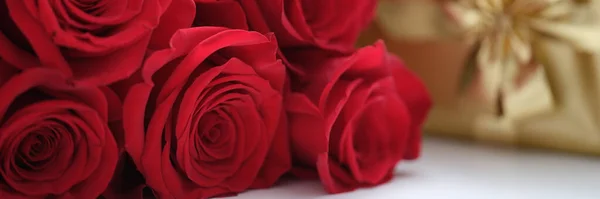 白いテーブルの上に新鮮な赤いバラと黄金のギフトボックス バレンタインデーと女性のための驚き — ストック写真