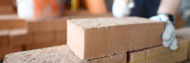 Brick orange wall set laying inside partition room at construction site. Construction worker ironing brick concept