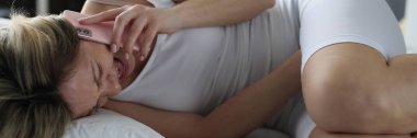 Karın ağrısı olan hasta bir kadın yatakta uzanıyor ve doktorla telefonda konuşuyor. Karın ağrısından muzdarip mide sorunları.