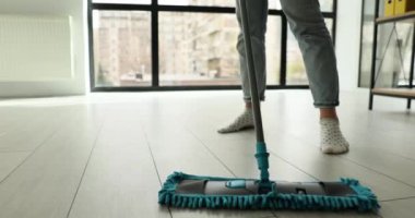 Ev hanımı ev işleri yapıyor. Isıtılmış ahşap döşemeleri ıslak paspasla temizliyor. Rutin ev işleri ve ev işi uzmanlık konsepti.