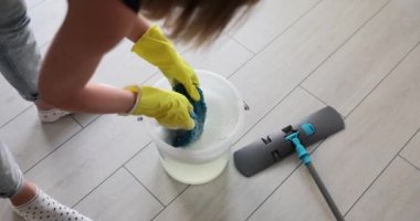 Temizlikçi kadın kovaya bez sıkıştırıyor. Deterjanla ıslak bez sıkan kadın.