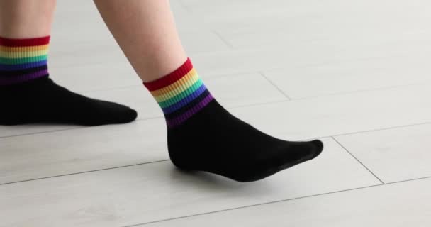 装飾されたLgbtの旗を持つ靴下の女性が床を歩いています 性的マイノリティーを支援するデモ — ストック動画