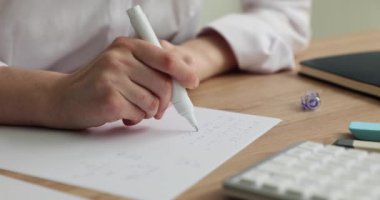 Öğrenci matematikte örnekler çözer ve hatayı düzelticiyle siler. Beyaz renk düzeltici ve hata düzeltme