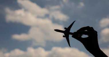 Mavi gökyüzüne karşı model uçak tutan yolcu ya da pilot. Hava seyahati.