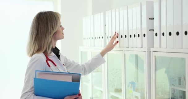 Administrador Clínica Médica Encuentra Carpeta Requerida Tarjeta Del Paciente Estante — Vídeo de stock