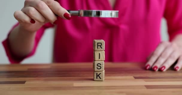 女性は虫眼鏡で木製のリスクブロックを調べます 意思決定におけるリスク管理 — ストック動画