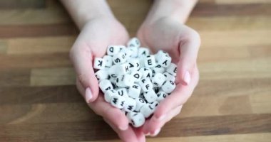Kadın eli, içinde harfler olan beyaz plastik küpleri tutuyor. Eğitim ve dil öğrenme kavramı