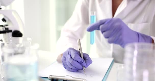 Laboratuvar Asistanı Notlar Alır Test Tüpünü Mavi Sıvıyla Tutar Gözlemleri — Stok video