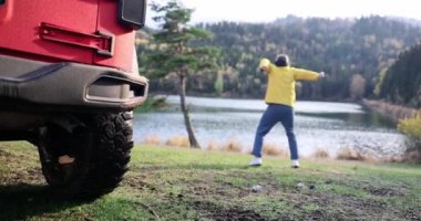 Male tourist traveler joyful jumping near a mountain lake. Goal achievement and travel motivation concept