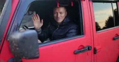 Smiling male SUV driver waving hand in greeting. Offroad adventure hunters