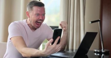 Happy man looking at phone screen and celebrating online victory. Emotions of financial monetary success and successful business contract