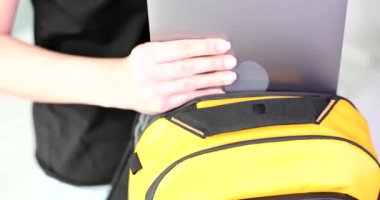 Woman puts laptop in sports backpack. Transportation of computer equipment while traveling