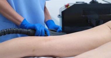 Female cosmetologist makes laser hair removal procedure for legs of patient in beauty salon. Professional cosmetic procedures in beauty clinic