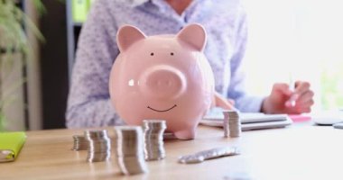 Woman counts financial savings on calculator with piggy bank. Control of expenses and cash income