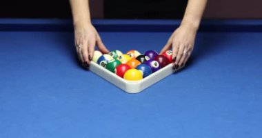 Kadınlar gece kulübünde üçgen raflarda bilardo topları düzenler. Bilardo oyunu