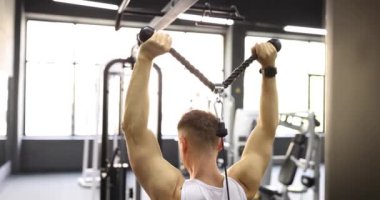 Spor salonunda egzersiz yapan ve spor salonunda ağırlık kaldıran bir adam. Spor salonunda traksiyon makinesi.