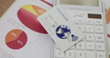 Hesap makinesinin üzerinde beyaz plastik bir banka kartı var, yakın plan. Mevduat için elverişli koşullar, kredi geçmişi