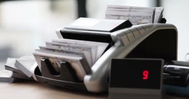 Masadaki sayım makinesi dolarları yakın plan olarak görüyor. Nakit hesaplama için modern ekipman
