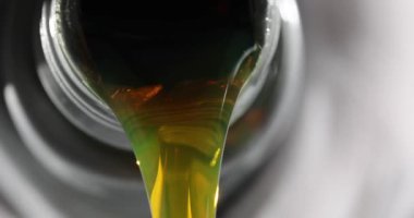 Sarı yağ akışı plastik bir teneke kutudan, yakın plandan geliyor. Yağ değişimi, yakıt eksikliği.