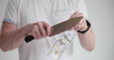 Bir adam keskin bir bıçakla 100 dolarlık banknot kesiyor. Para kaybı kavramı, mali kriz