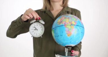 Bir kadın elinde bir küre ve çalar saat tutuyor, yakın plan. Kavram, dünya zamanı, Greenwich meridyeni
