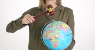 Bir iş kadını bir yargıcın çekicini ve bir küreyi elinde tutuyor. Yakın plan. Kavram, uluslararası mahkeme, insan hakları