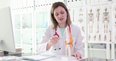 Ortopedik doktor bacağındaki eklemlerin hareketliliğinden bahsediyor, yakın plan. Dizin anatomik modeli.