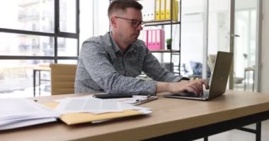 Ofiste laptopunu daktilo eden uykulu bir iş adamı, yakın plan. İş yerinde uyuşukluk, takip