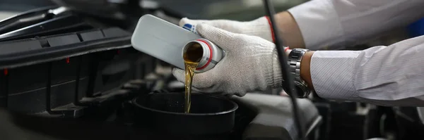 自動車整備士はオイルの缶から車のエンジンにオイルを注ぐ 車のコンセプトのオイル交換 — ストック写真