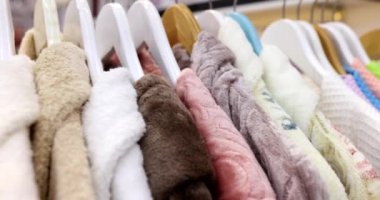 Terry bornozları mağazada asılı duruyor. Bornozlar farklı renklerde bulunur. Dükkanda asılı dururlar.