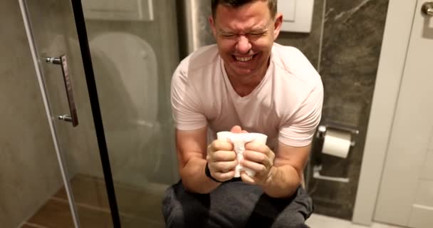 男はトイレットペーパーでトイレに座り 便秘を患っている 下痢性腹痛や痙攣に苦しむ者 — ストック動画
