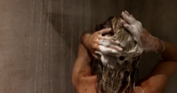 ヘアケア付きシャワーでシャンプーで髪を洗う女性 女の子はリンスシャンプーとバームを使用しています — ストック動画