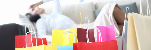 Multicolored bags with purchases on background of tired woman. Fatigue depression and shopping