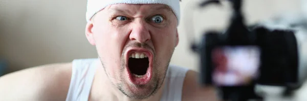 Emotionally angry sports blogger man screaming at camera. Sport motivation perseverance and remote training concept