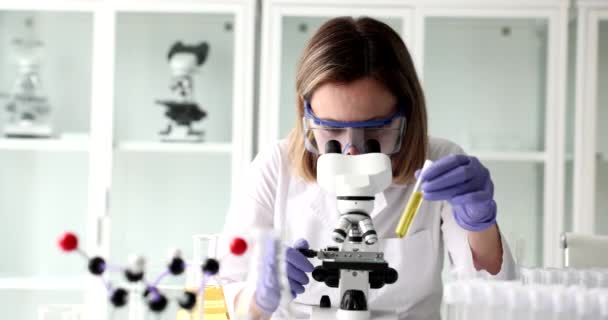 Químico Mira Microscopio Sostiene Tubo Ensayo Con Líquido Amarillo Biológico — Vídeo de stock