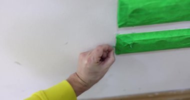 Erkek müteahhit prizden yeşil bant çıkarır. Prizleri korumak, onarmak ve duvarları boyamak.